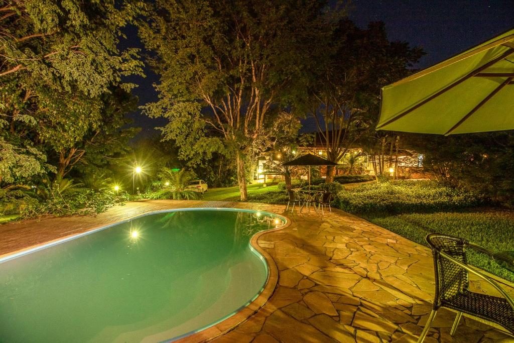 Piscina iluminada à noite cercada de jardim